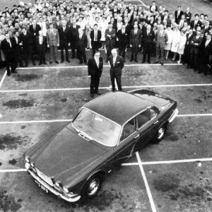 Sir William and Bill Heynes, showcasing the new XJ - with factory staff - in an oil-stained company carpark.